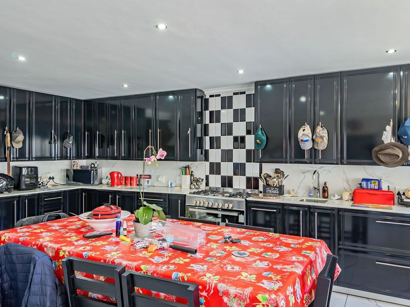 Spacious kitchen featuring modern black gloss cabinetry, marble-look benchtops, a gas cooktop, and a distinctive checkerboard tile splashback.