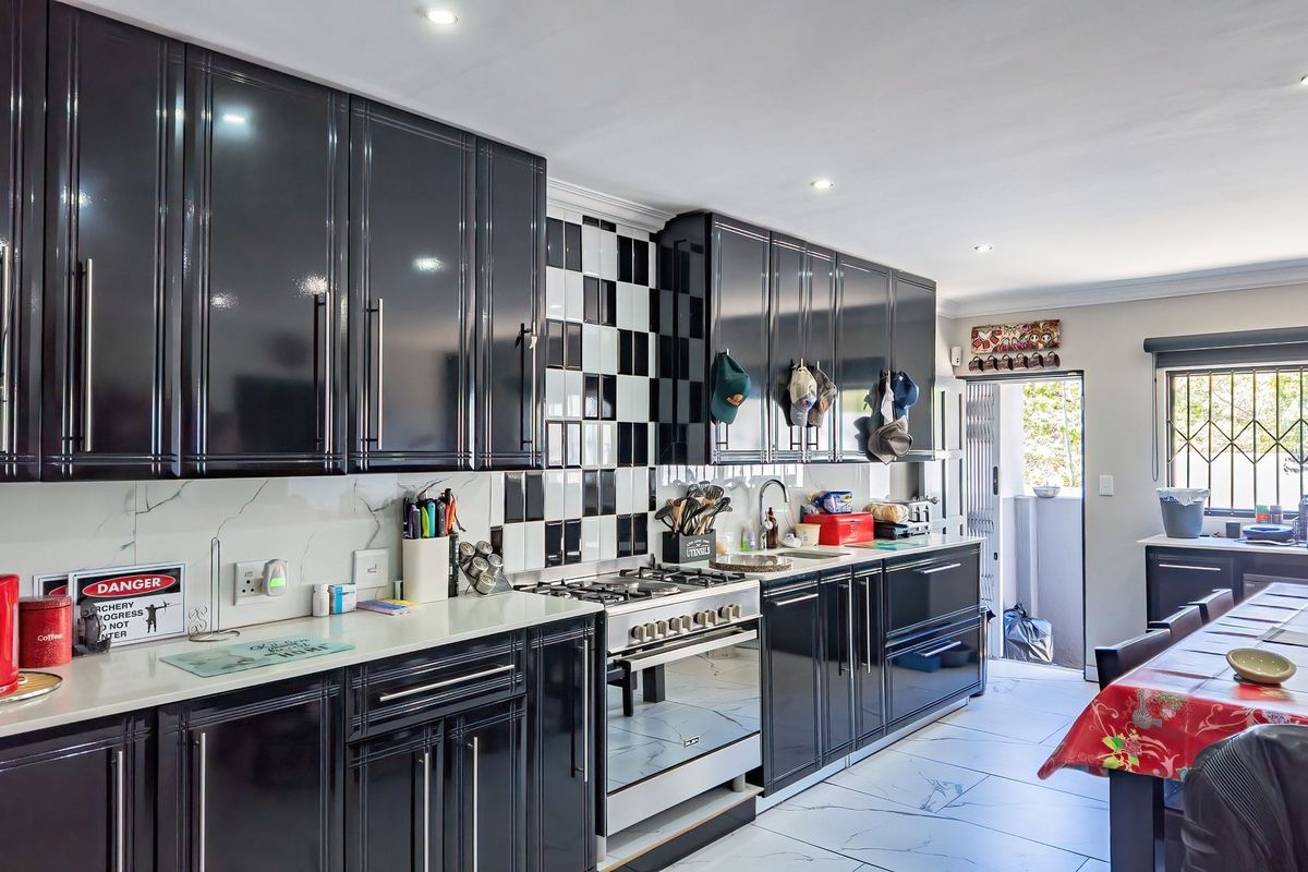 Modern kitchen featuring high-gloss black cabinetry, a gas hob with built-in oven, checkered tile backsplash, and marble-look flooring with direct access to the exterior.