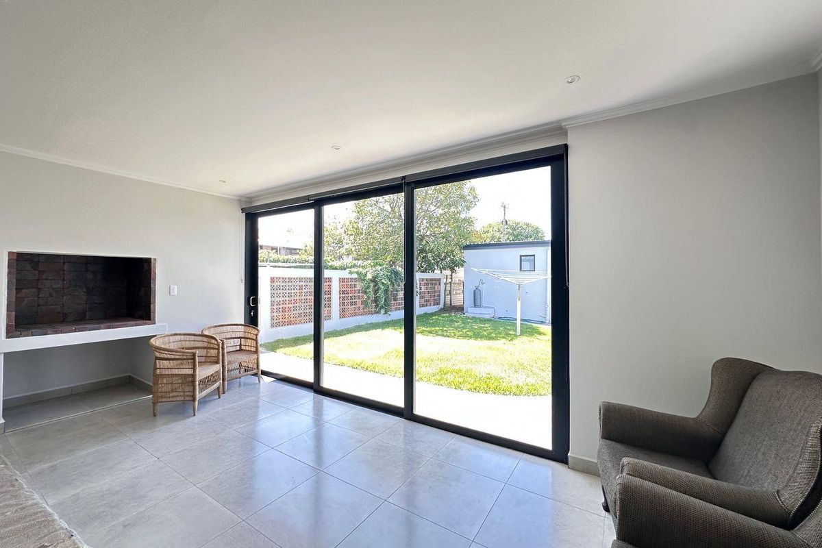 Bright living room featuring large sliding glass doors that open to the garden, complemented by a built-in fireplace and modern tiled flooring.