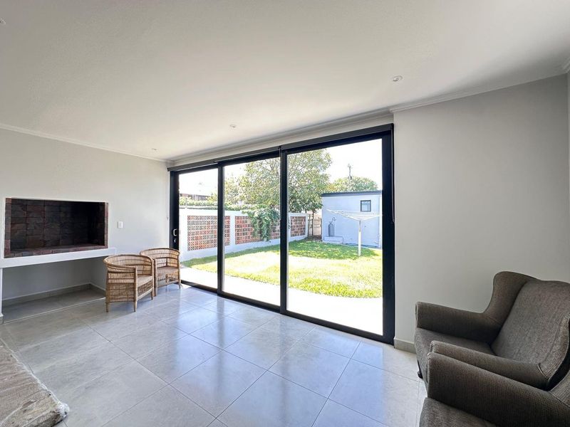 Bright living room featuring large sliding glass doors that open to the garden, complemented by a built-in fireplace and modern tiled flooring.