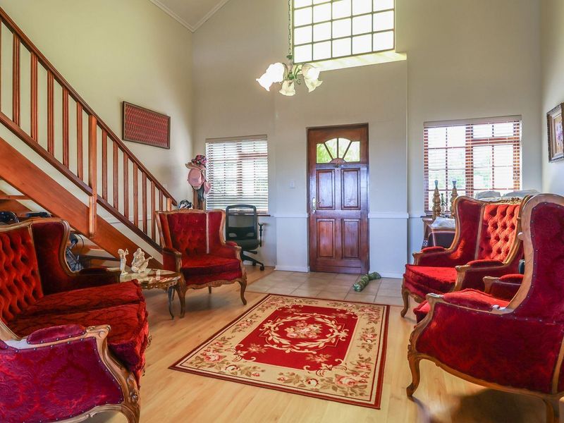 Spacious living area featuring high ceilings, a wooden staircase with balustrade, and a classic wooden front entrance door with a transom window.