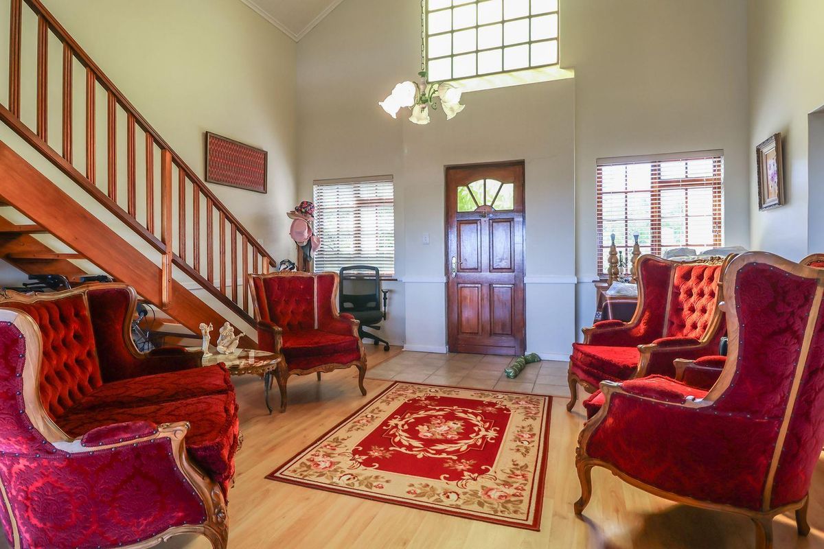 Spacious living area featuring high ceilings, a wooden staircase with balustrade, and a classic wooden front entrance door with a transom window.