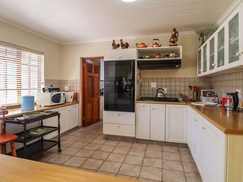 A functional kitchen featuring white shaker-style cabinetry, tiled backsplash, laminate countertops, built-in oven, and gas hob with an extractor fan.