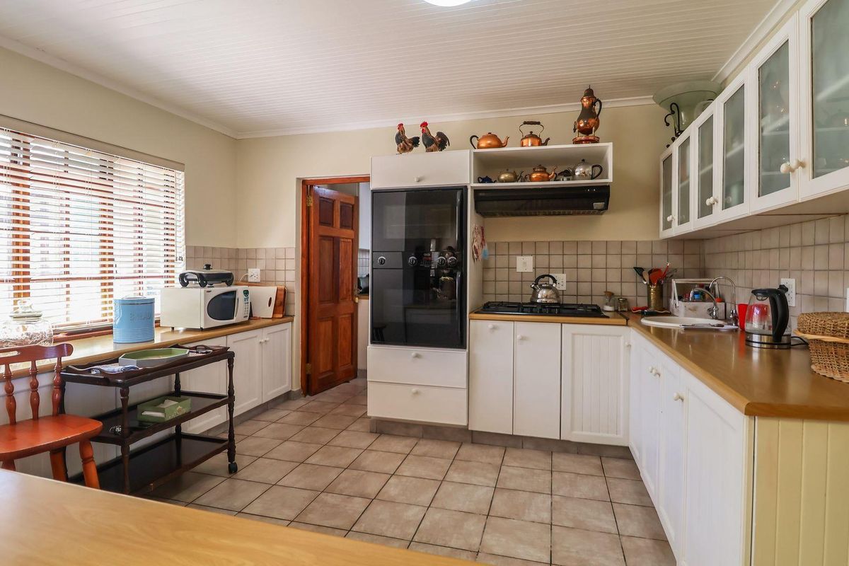 A functional kitchen featuring white shaker-style cabinetry, tiled backsplash, laminate countertops, built-in oven, and gas hob with an extractor fan.