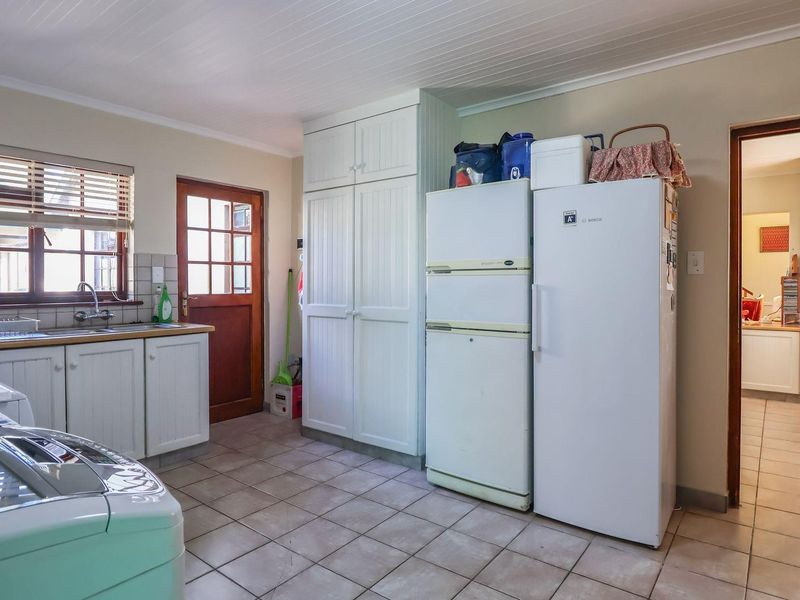 Functional laundry room featuring built-in cabinetry, tiled flooring, and direct exterior access through a timber-framed door.