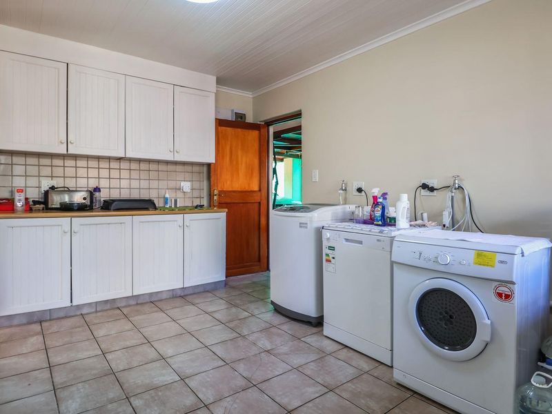 A functional laundry room featuring built-in cabinetry, tiled flooring, and dedicated plumbing connections for appliances.