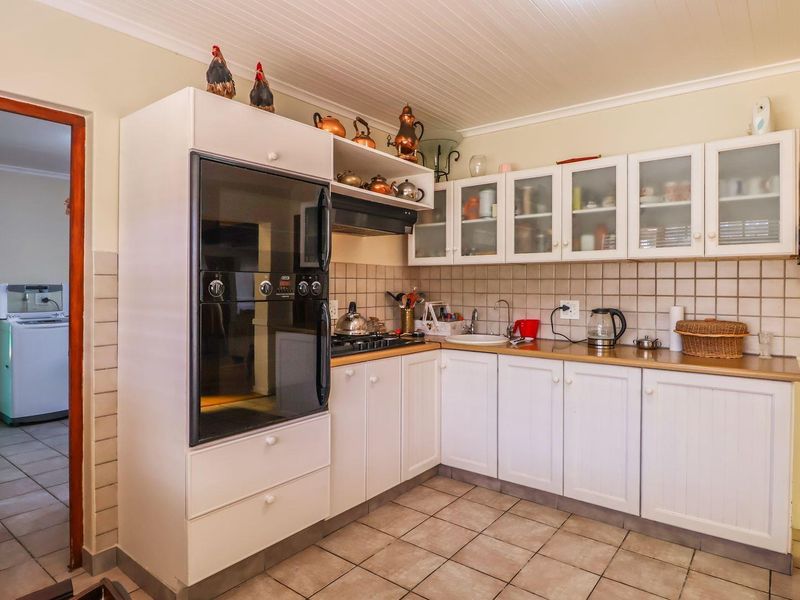 A functional kitchen featuring white cabinetry, tiled backsplash, built-in oven, gas hob, and tiled flooring, offering a practical layout for daily meal preparation.