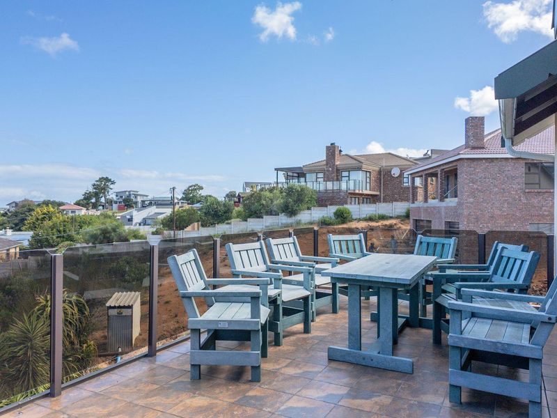 Spacious elevated balcony featuring tiled flooring and a modern glass balustrade, offering expansive views of the surrounding residential neighbourhood.