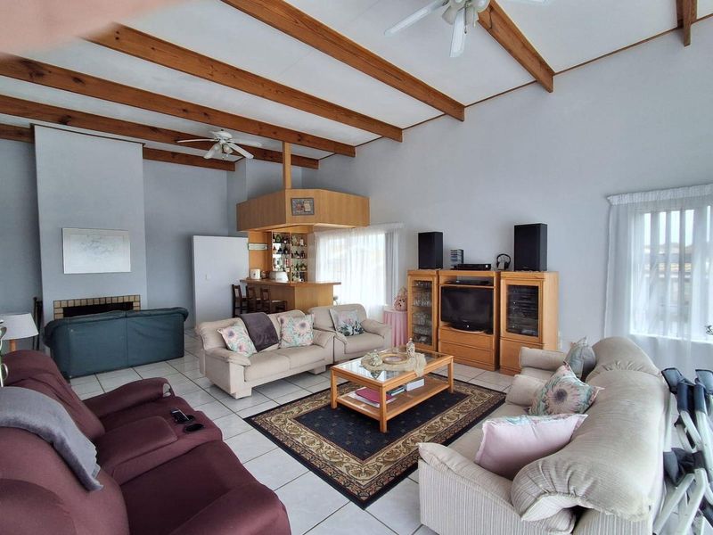 Spacious living room featuring exposed timber ceiling beams, a built-in bar area, a fireplace, and tiled flooring throughout.