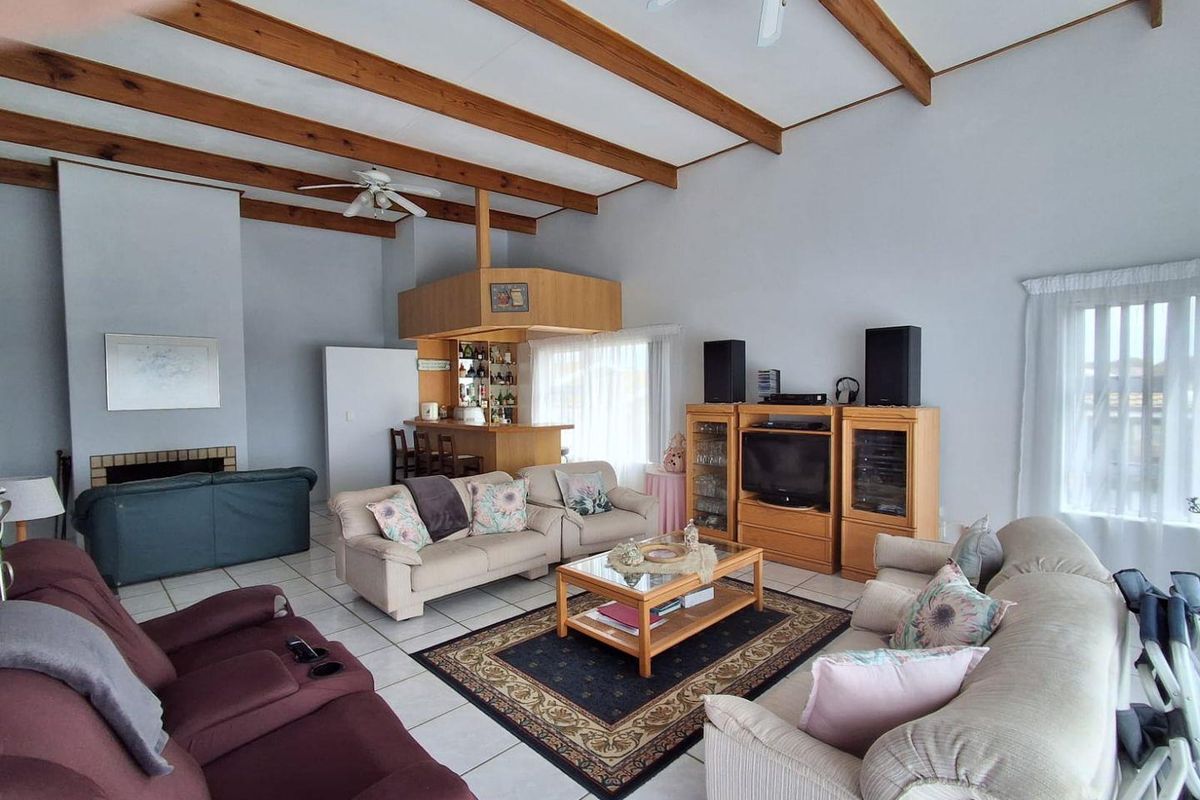 Spacious living room featuring exposed timber ceiling beams, a built-in bar area, a fireplace, and tiled flooring throughout.