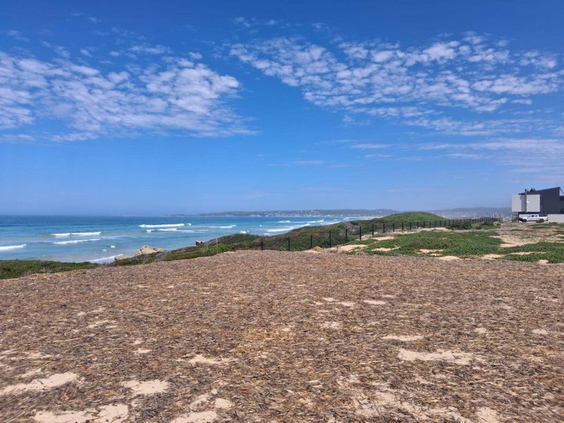 A scenic view of the coastline from the vacant residential land, featuring natural vegetation and perimeter fencing.