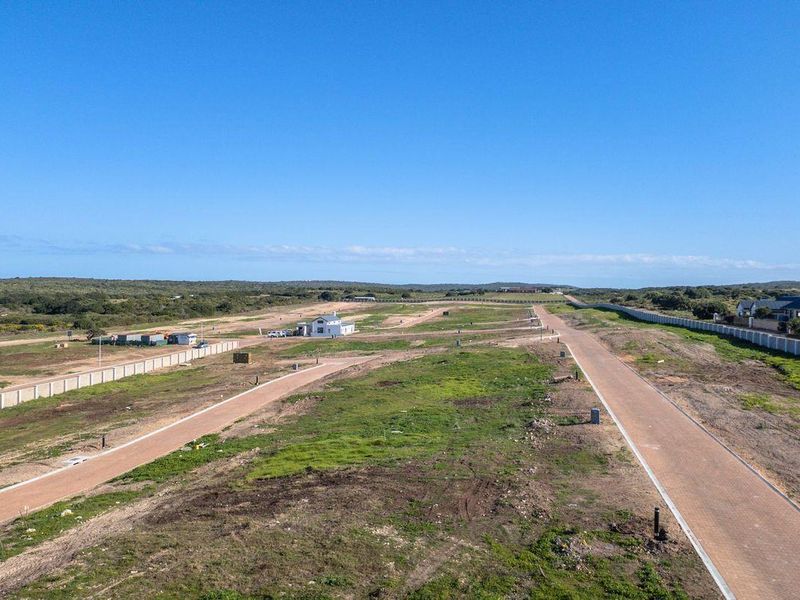 An aerial view of a residential development site featuring paved roads, perimeter walling, and established street lighting infrastructure.