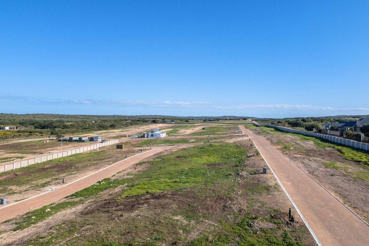An aerial view of a residential development site featuring paved roads, perimeter walling, and established street lighting infrastructure.