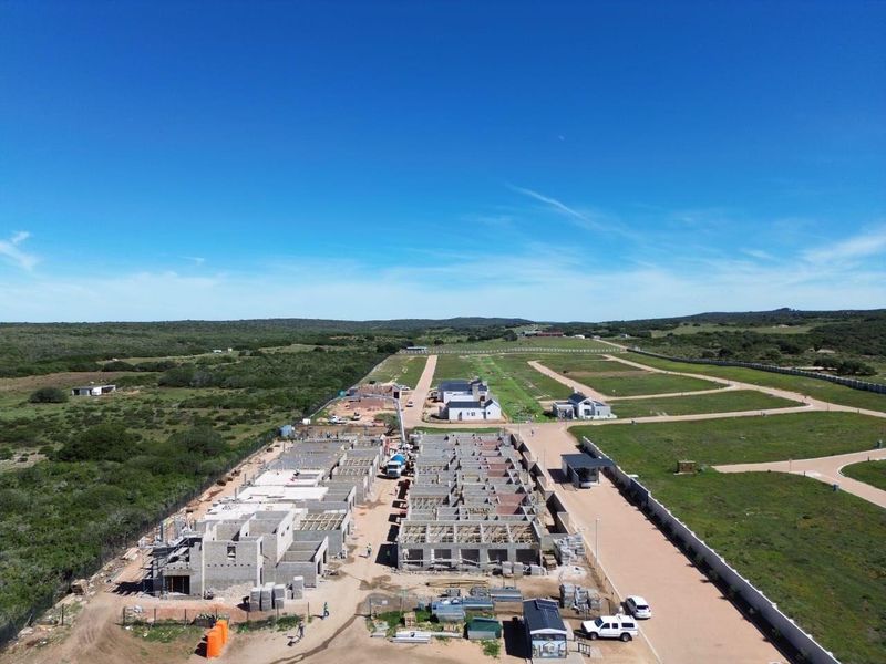 Aerial view of a residential development site showing multiple properties under construction with established road infrastructure and perimeter fencing.