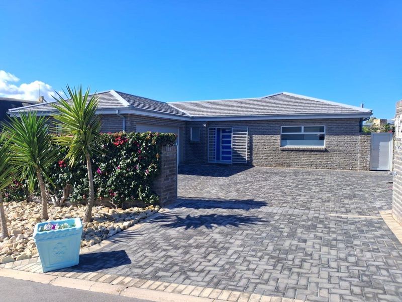 A well-maintained single-story brick home featuring a paved driveway, secure entrance gate, and a clean, modern exterior facade.