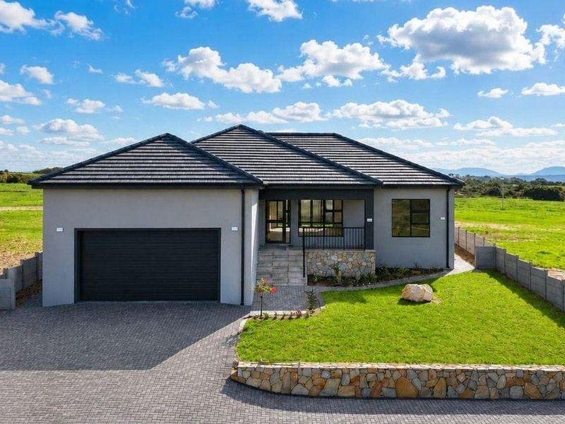 Modern single-story house featuring a tiled roof, stone cladding accents, a paved driveway, double garage, and a well-maintained front garden.