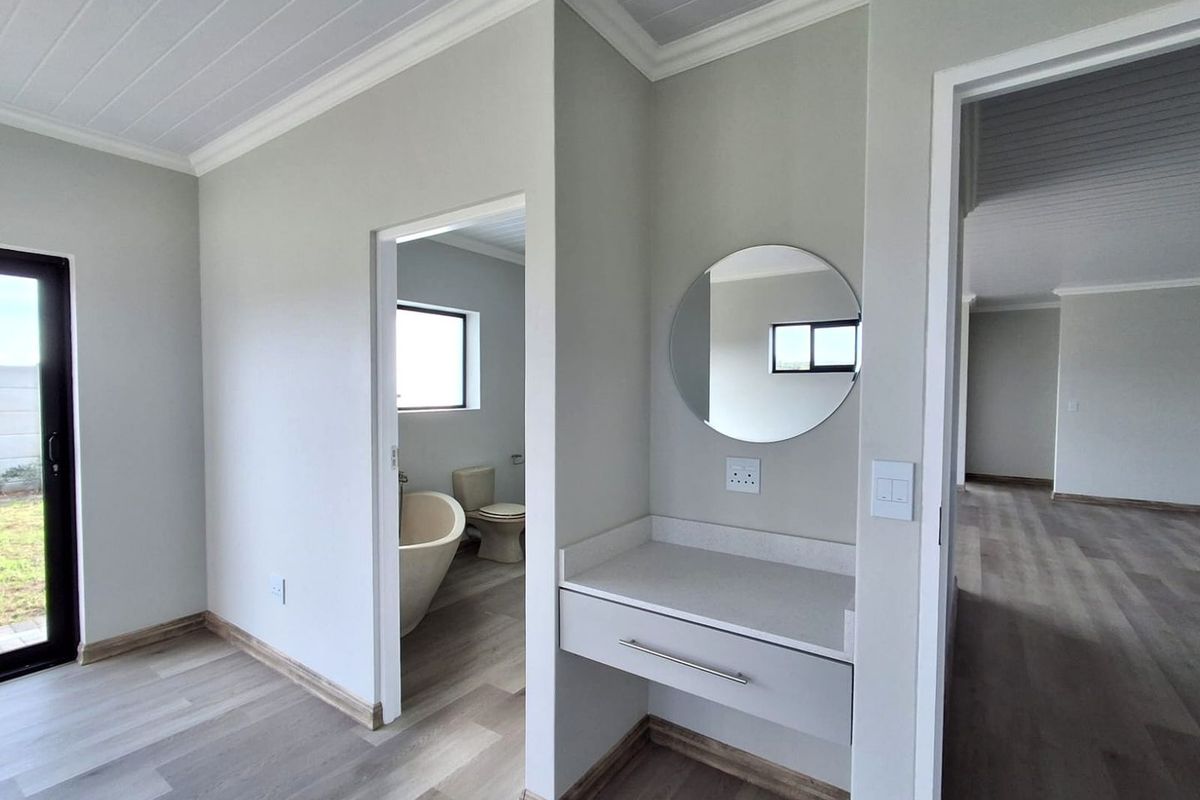 Modern bathroom featuring a freestanding bathtub, toilet, and a sleek vanity with stone countertop, finished with light laminate flooring and a clean aesthetic.