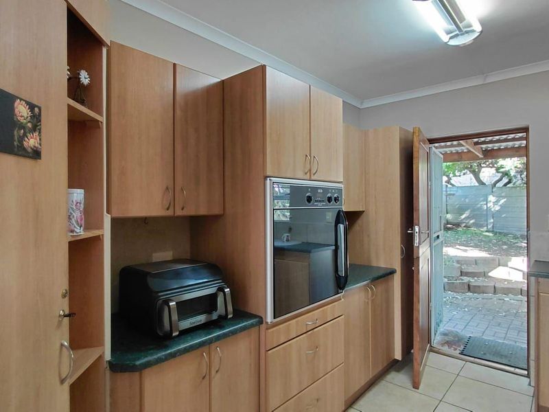 Kitchen featuring wooden cabinetry, laminate countertops, and a built-in oven, with direct access to the rear outdoor area.