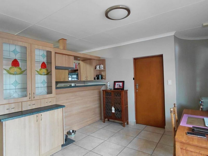 Open plan living area featuring tiled flooring, built-in cabinetry with decorative glass inserts, and a breakfast bar counter.