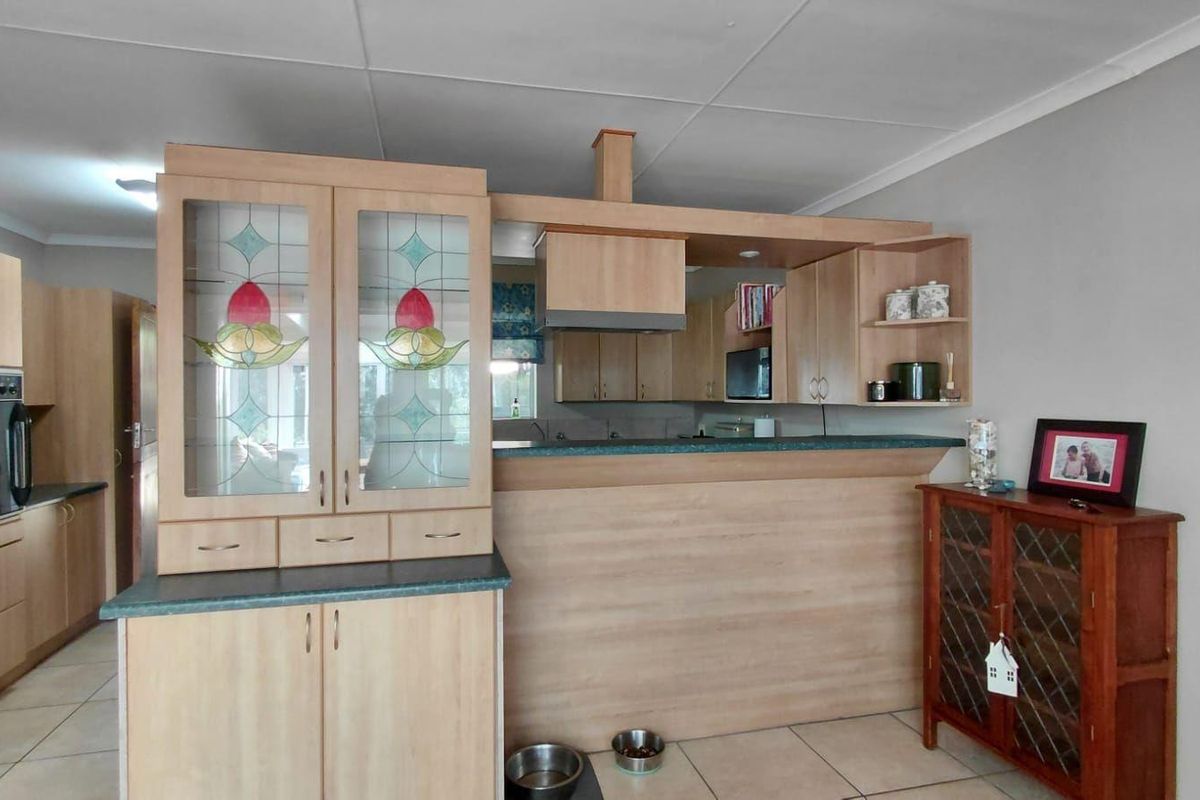 A functional kitchen featuring light wood cabinetry, a breakfast bar, built-in oven, extractor fan, and tiled flooring.