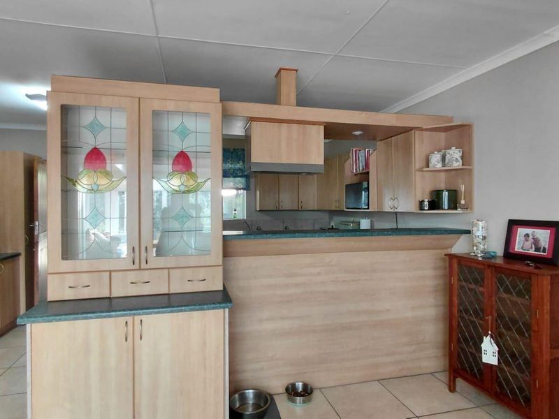 A functional kitchen featuring light wood cabinetry, a breakfast bar, built-in oven, extractor fan, and tiled flooring.