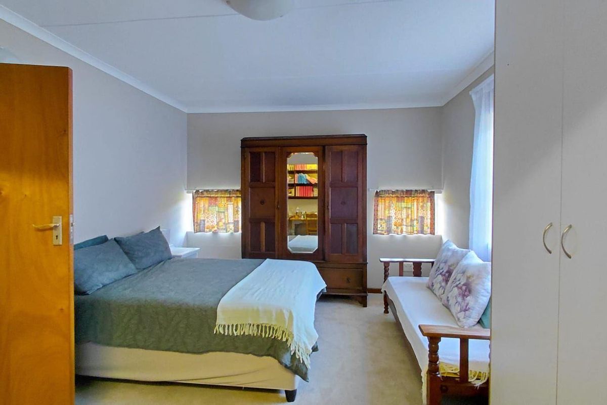 A functional bedroom featuring neutral wall finishes, carpeted flooring, and built-in cupboard storage.