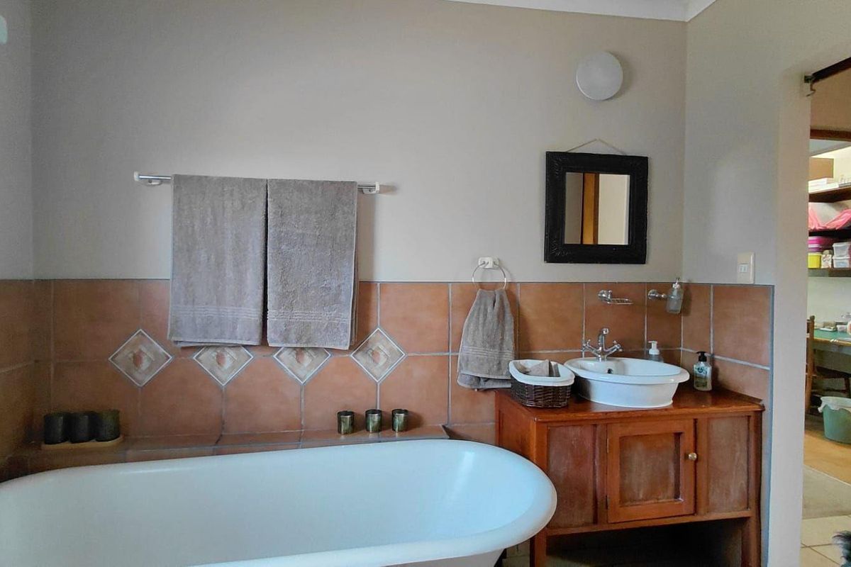 A bathroom featuring a freestanding bathtub, a vessel sink set on a wooden vanity, and decorative ceramic wall tiling.