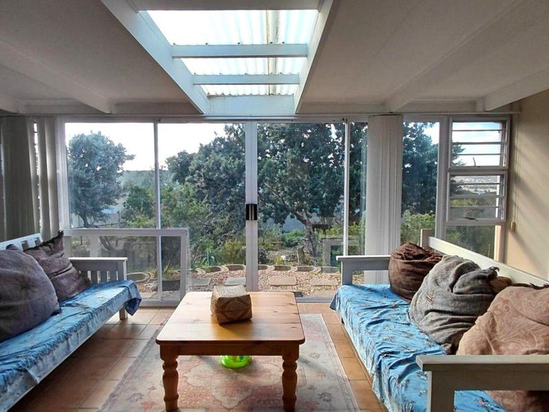 A sun-filled enclosed patio featuring large sliding glass doors, a skylight roof, and tiled flooring, offering a bright space with views of the garden.