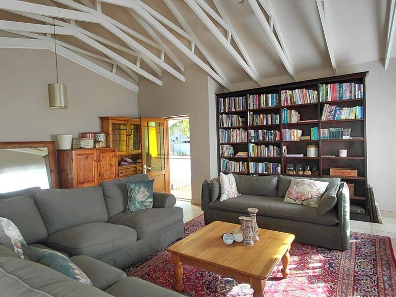 Spacious living room featuring a high vaulted ceiling with exposed white trusses and a large built-in floor-to-ceiling bookshelf.