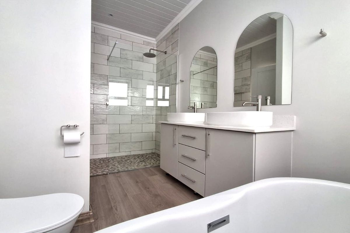 Modern bathroom featuring a double vanity with vessel sinks, a spacious walk-in shower with pebble flooring, and a sleek freestanding bathtub.