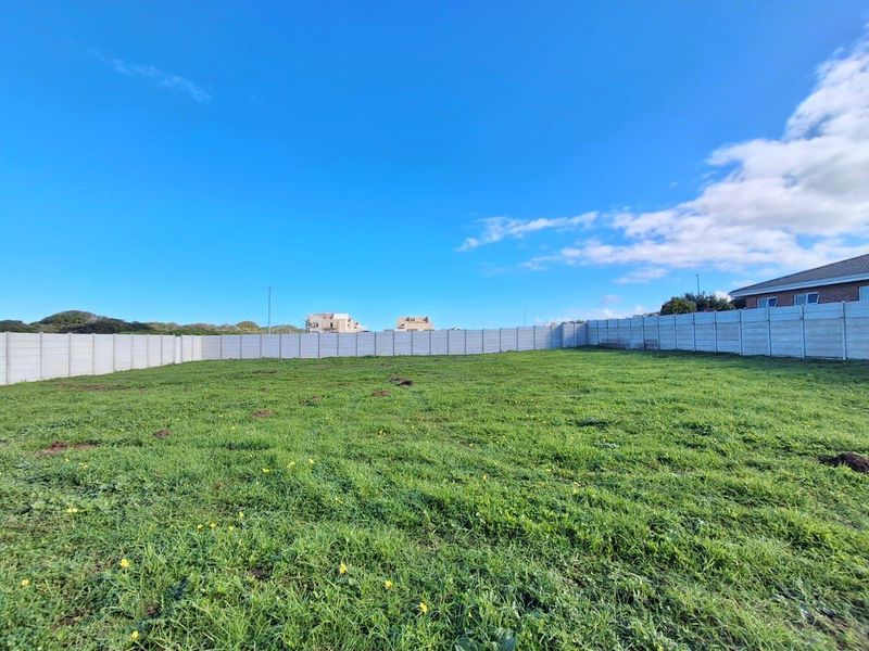 A vacant residential plot featuring a level grassed area enclosed by precast concrete boundary walls.