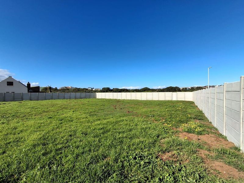 A vacant residential plot featuring a level grassed area enclosed by precast concrete boundary walls.