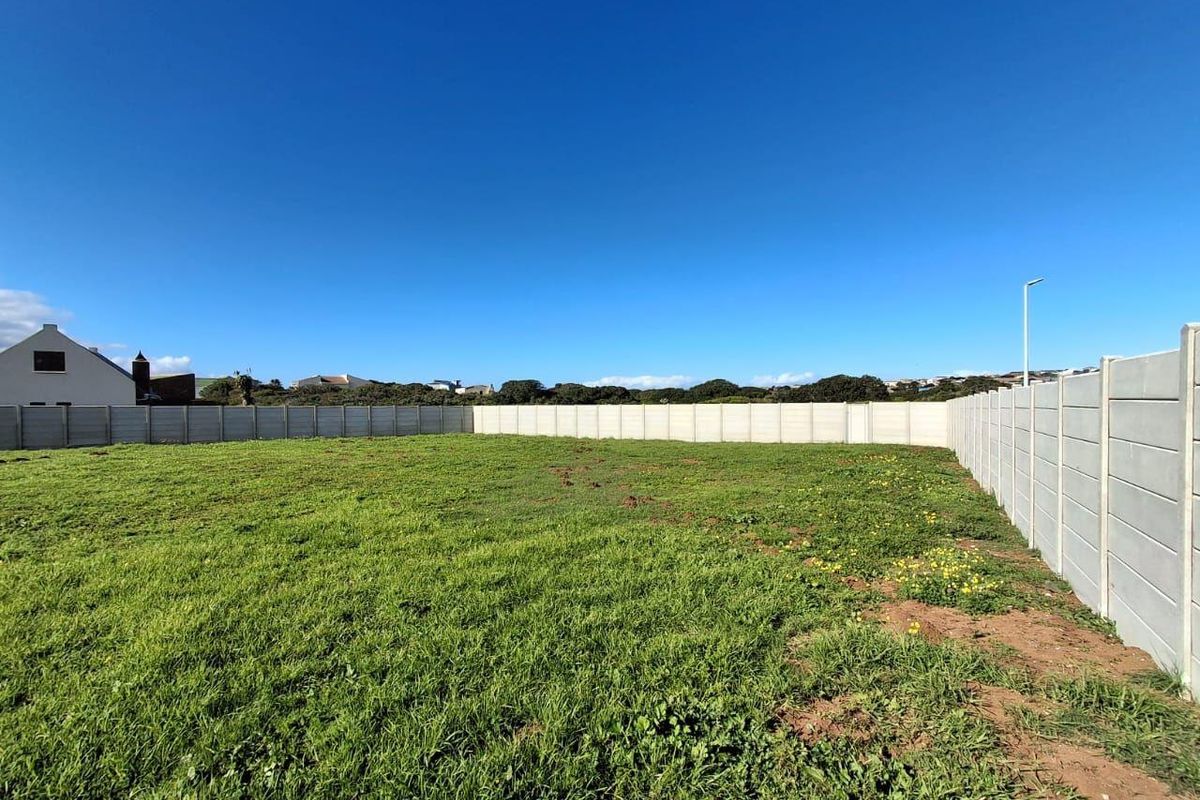 A vacant residential plot featuring a level grassed area enclosed by precast concrete boundary walls.