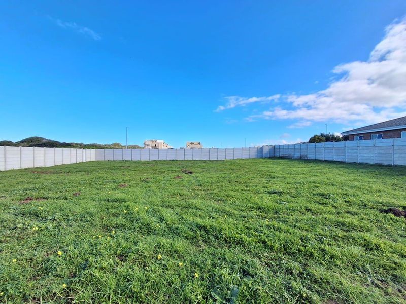 A vacant residential plot featuring a level grassed area enclosed by a precast concrete boundary wall.