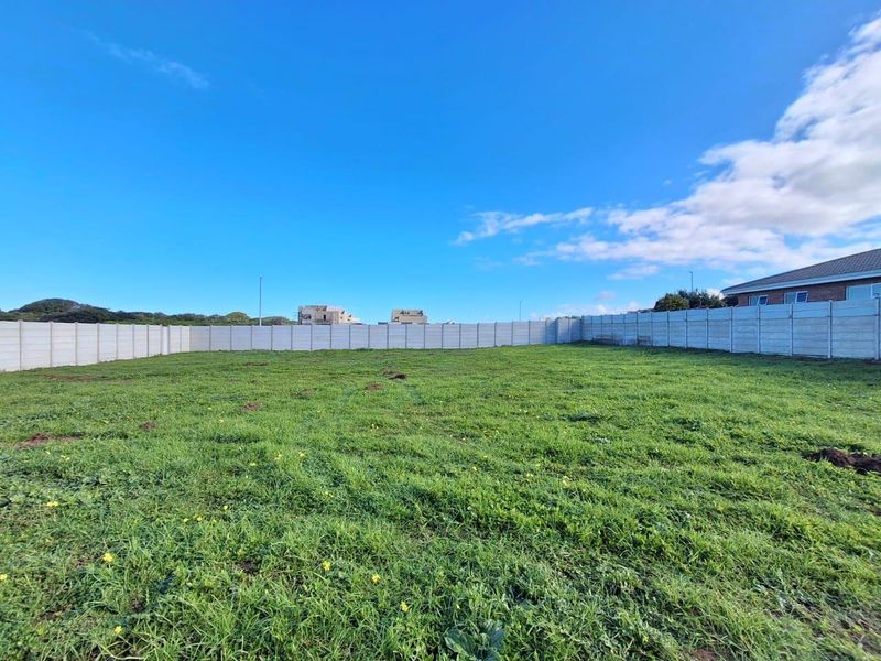 A vacant residential plot featuring a level grassed area enclosed by a precast concrete boundary wall.