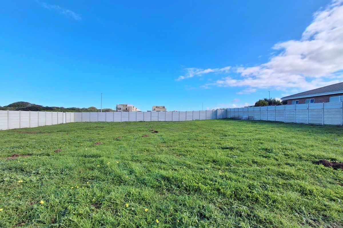 A vacant residential plot featuring a level grassed area enclosed by a precast concrete boundary wall.