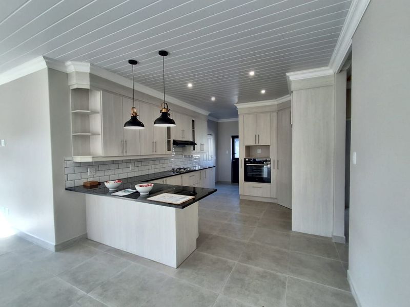 Modern kitchen featuring light wood cabinetry, dark stone countertops, subway tile backsplash, built-in oven, and a stylish tongue and groove ceiling.