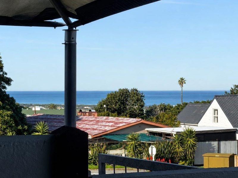 A covered balcony area offering an elevated view of the surrounding neighborhood and the distant ocean horizon.