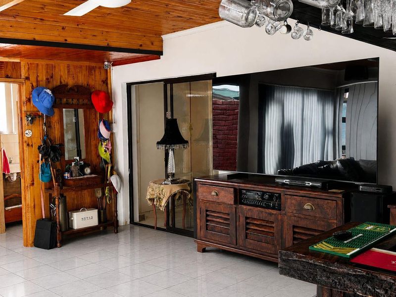 Living area featuring timber ceiling and wall paneling, tiled flooring, and sliding glass doors providing access to adjacent spaces.