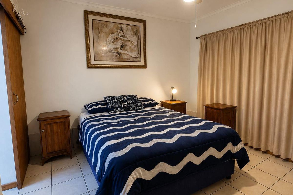 A functional bedroom featuring tiled flooring, a ceiling fan, and a built-in wardrobe, offering a neutral base for personalization.