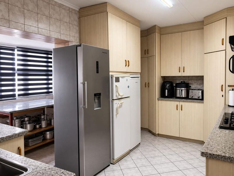 A functional kitchen featuring light wood-tone cabinetry, granite countertops, tiled flooring, and a tiled backsplash, offering ample storage and workspace.