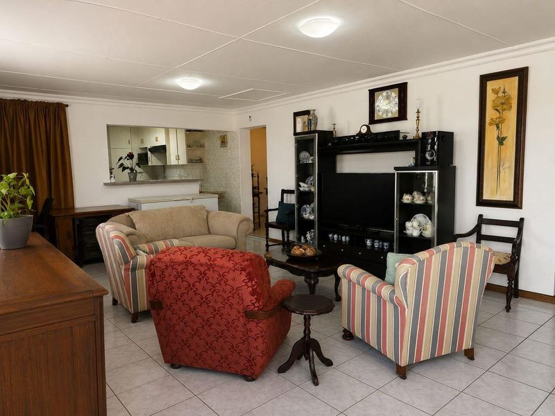 Open plan living area featuring tiled flooring and a convenient pass-through window connecting to the kitchen space.
