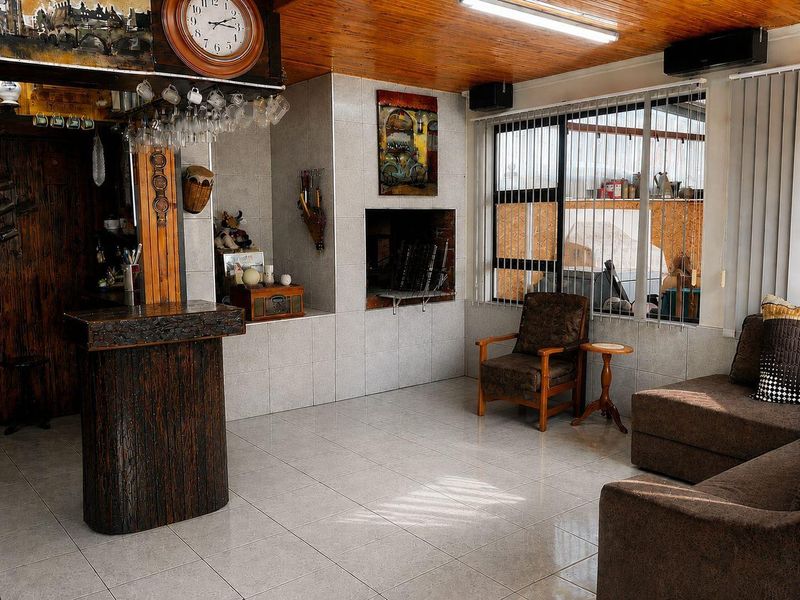 A dedicated bar area featuring a built-in counter, tiled flooring, a timber-clad ceiling, and a built-in fireplace, offering a cozy space for entertainment.