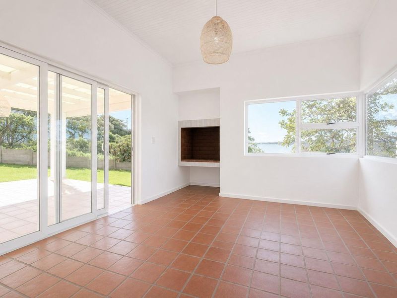 Bright and spacious living area featuring terracotta floor tiles, a built-in fireplace, and large sliding doors opening to a patio with garden views.