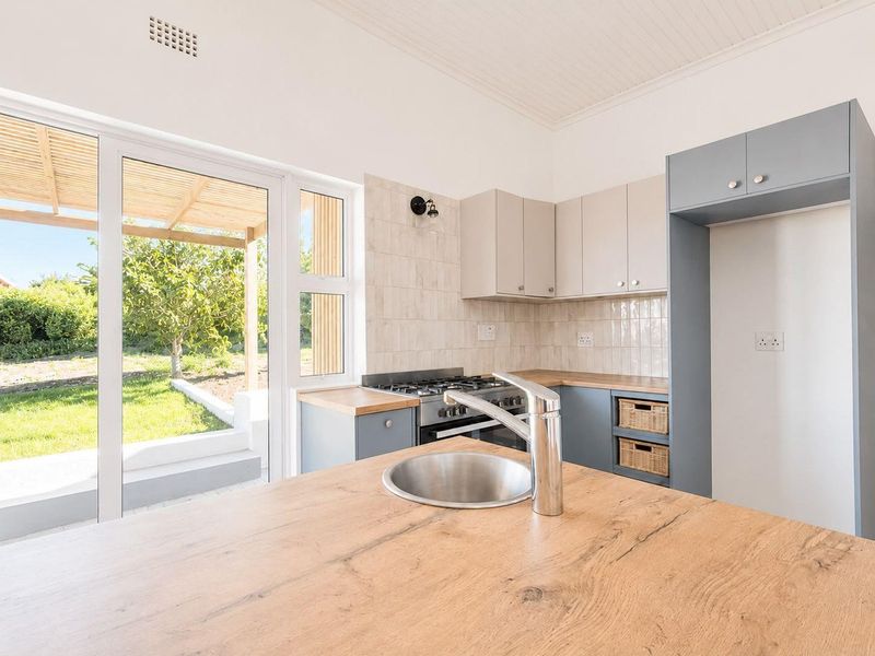 Modern kitchen featuring wooden countertops, built-in cabinetry, gas hob, and direct access to the outdoor patio area through sliding glass doors.