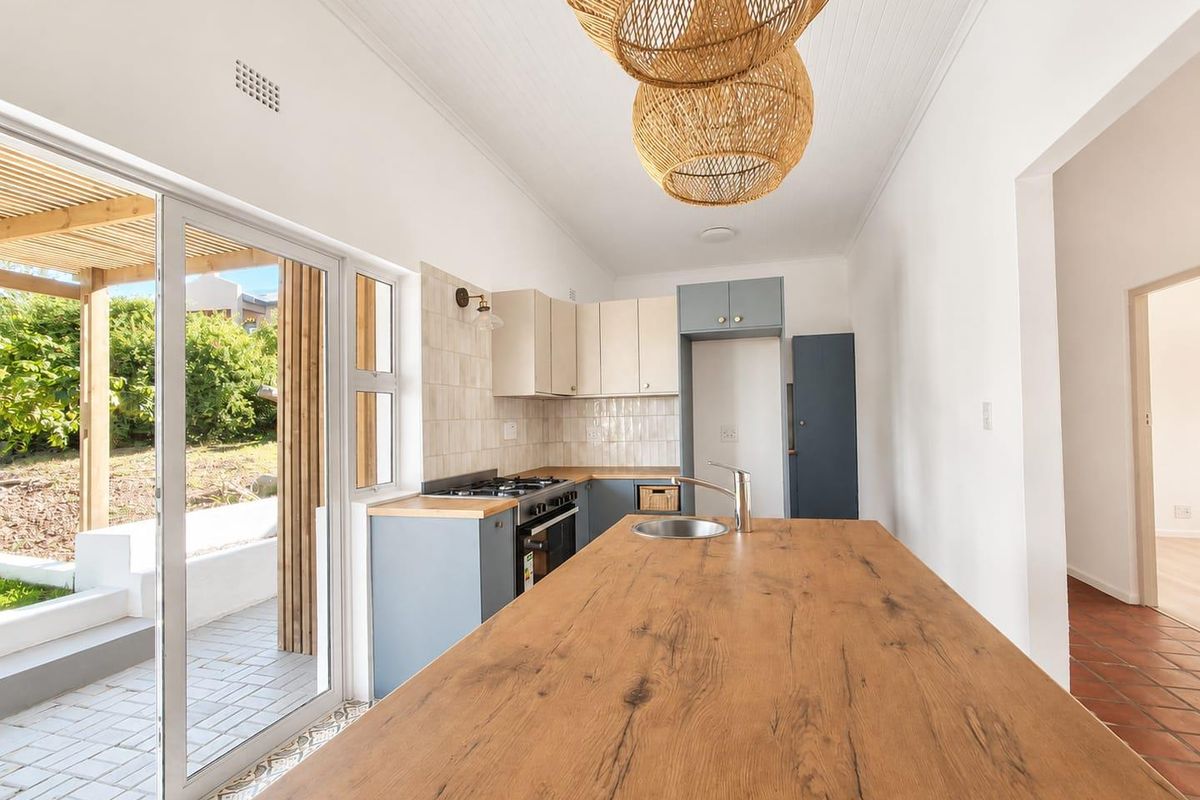 Modern kitchen featuring a timber-topped island, built-in cabinetry, gas hob, and direct access to an outdoor patio area through sliding glass doors.