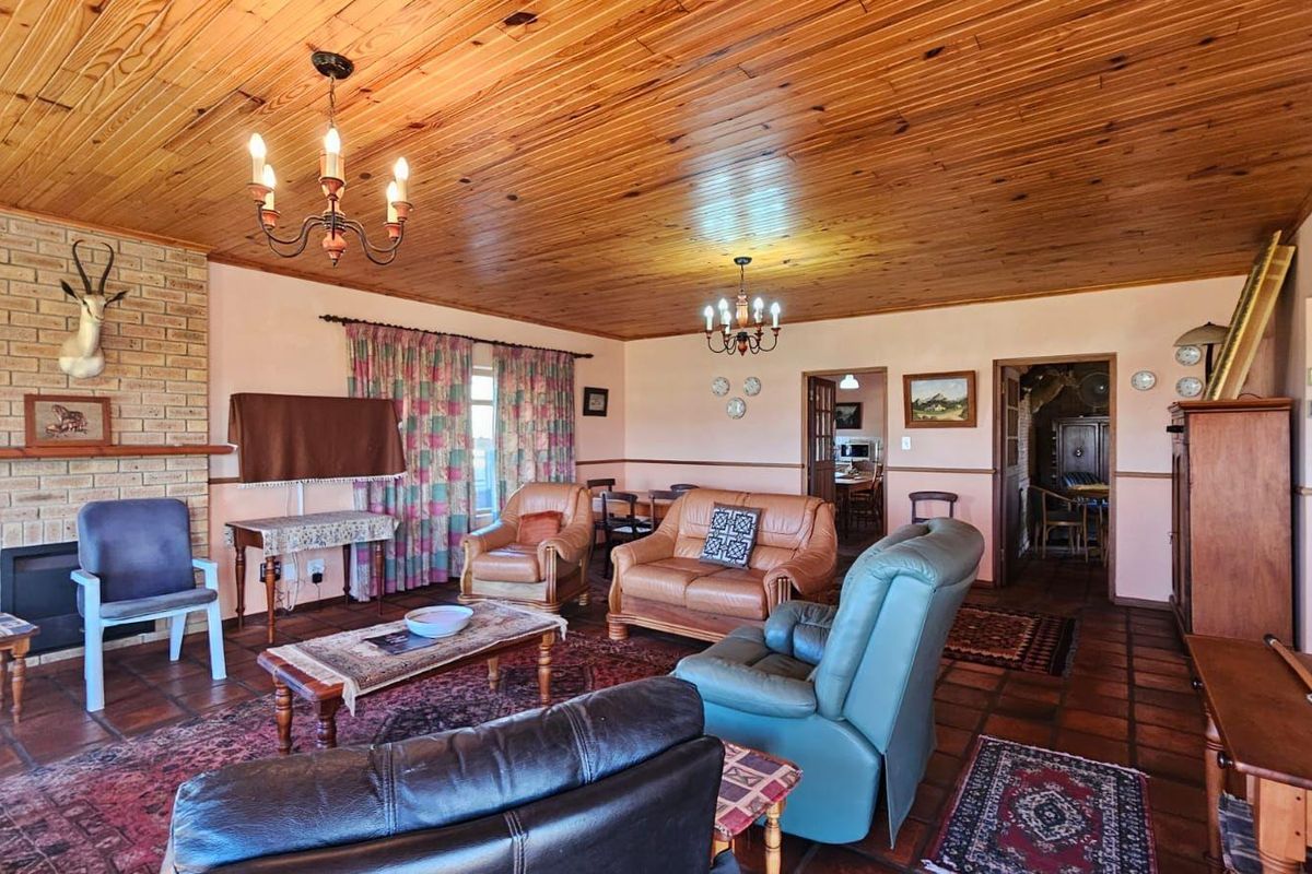 Spacious living room featuring a brick fireplace, warm timber ceiling, and traditional terracotta floor tiles, offering a classic and cozy atmosphere.