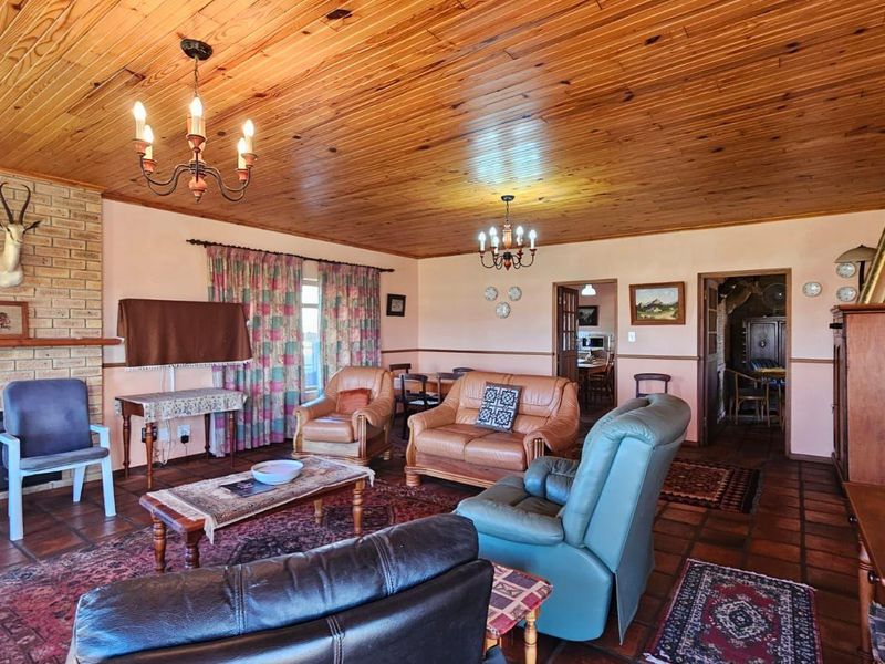 Spacious living room featuring a brick fireplace, warm timber ceiling, and traditional terracotta floor tiles, offering a classic and cozy atmosphere.