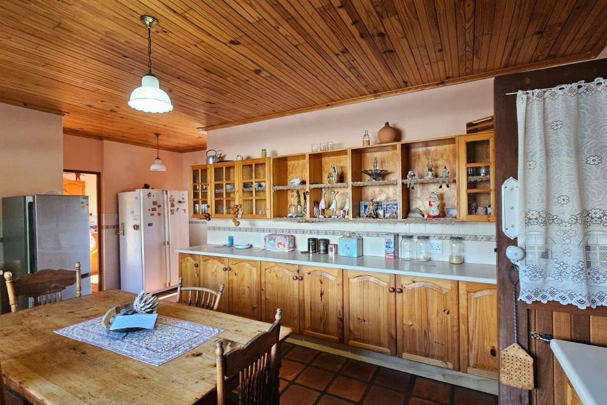 A rustic kitchen featuring extensive timber cabinetry, a wood-paneled ceiling, and tiled flooring, offering a warm and traditional aesthetic.