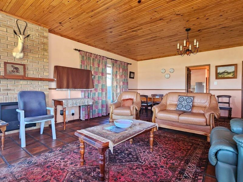 Spacious living room featuring a brick fireplace, traditional timber ceiling, and terracotta tiled flooring, offering a classic, dated aesthetic ready for modernization.